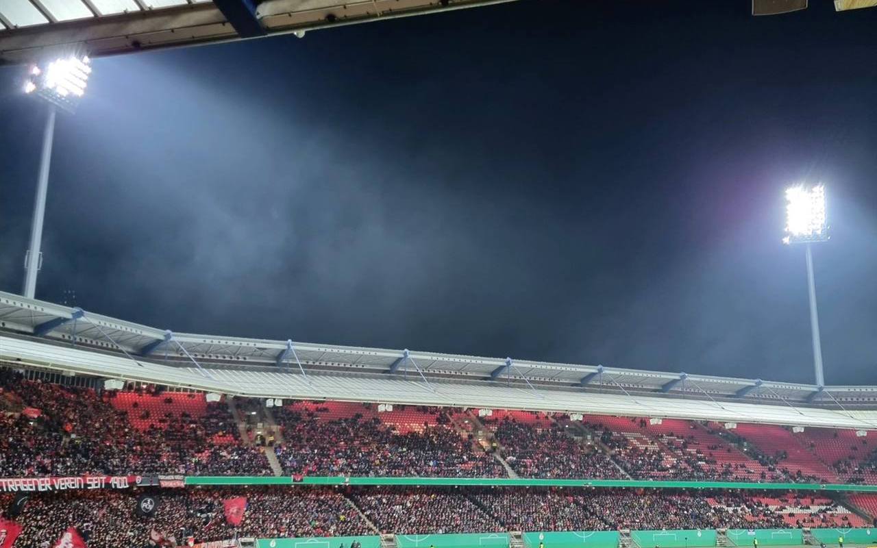 Stadion sepak bola penuh penonton di bawah lampu sorot